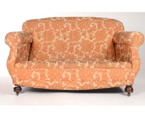 AN UPHOLSTERED TWO SEAT SOFA WITH S-SCROLL ARMS, BOWED APRON ON MAHOGANY STAINED BULBOUS WOODEN FEET FITTED WITH METAL CASTOR