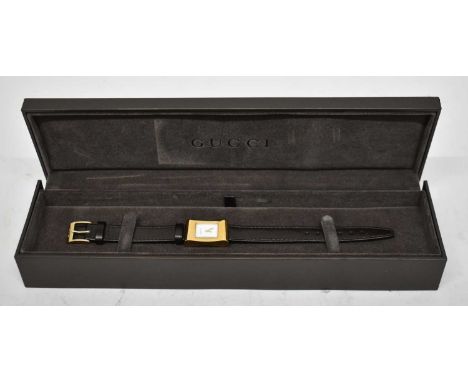 GUCCI; a lady's gold tone cocktail watch with logo to front and brown leather strap, in original box, unused with paperwork.