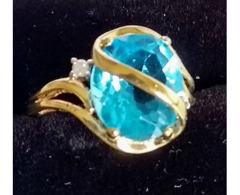 A 9ct yellow gold ring set with a blue topaz and a small diamond on either side, size M 1/2, 3.68g