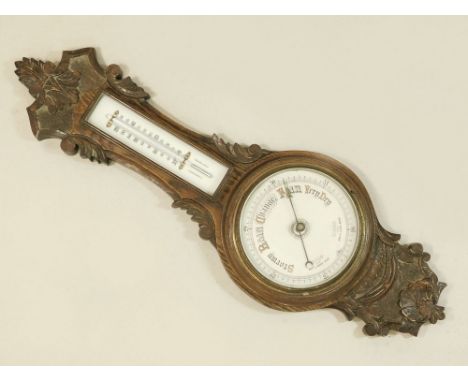 BAROMETER. An oak cased thermometer/barometer. Height 69cm.WE CANNOT SHIP THIS LOT due to fragility, size or weight. Our reco