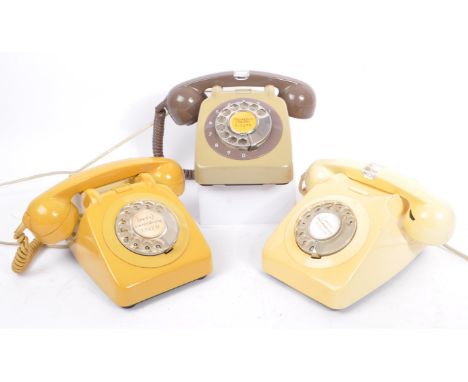 A collection of three mid 20th century rotary dial telephones. The telephones each in a yellow, cream, and olive green colour