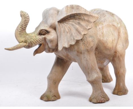 A large proportioned 20th century carved wood elephant. The decoration in the form of a walking elephant, with trunk raised. 
