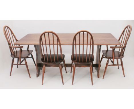 An oak refectory-style dining table and four Ercol Windsor dining chairs - the chamfered-edge top raised on shaped trestle su