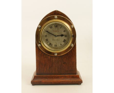 A 1930s Watford car clock mounted into an oak mantel-clock case - the 3in silvered dial with Roman numerals and signed 'Watfo