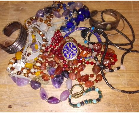 A bag of costume jewellery including stone beads, a yellow metal enamel locket etc. 