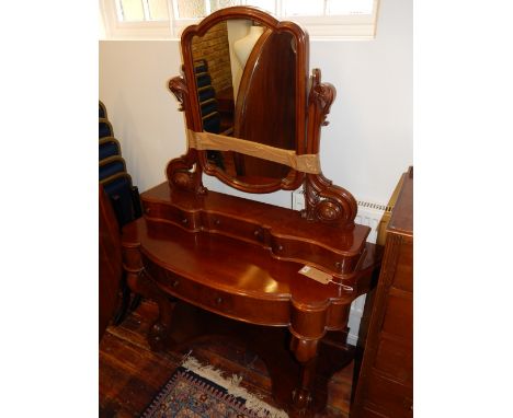 A Victorian mahogany dressing table, the raised back with a shaped rectangular mirror above an arrangement of drawers, on cab