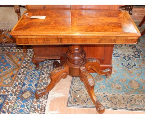 A Victorian walnut card table, having folding top above a turned and carved baluster support and raised on quadraped legs. L: