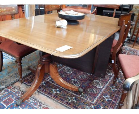 A George III style mahogany dining table, with turned pedestal supports and two leaf insertions, raised on tripod bases with 