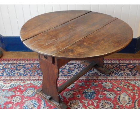 An 18th century and later walnut drop leaf table the circular top above chestnut shaped trestle supports, W. 110cm.