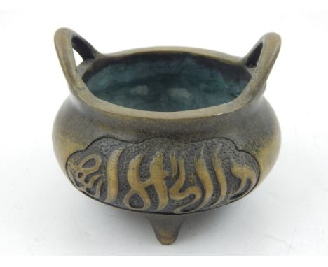 A Chinese bronze censor, having twin handles, decorated with characters, raised on three feet. 