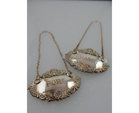 A pair of silver decanter labels for port and brandy, having scalloped shell and vine decoration, boxed. 