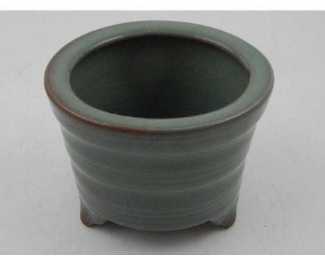 A Chinese celadon glazed ceramic incense burner of circular form, raised on three feet. H: 6.5cm W: 8.5cm