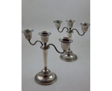 A pair of filled silver three light candelabra, of tapering cylindrical form on raised circular bases with husk borders, Birm