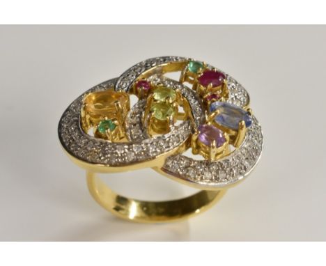 A diamond, ruby, emerald and coloured multi stone cluster ring, formed of three interlocking hoops of diamonds surrounding te