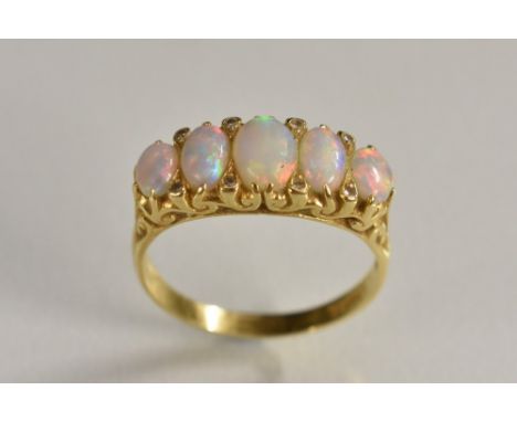 An 18ct gold five stone opal and diamond ring,five large graduated oval opal cabochons each flashing, red, green, violet and 