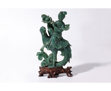 A JADE CARVING OF A LADY RIDING A PHOENIX
A lady wearing elegant flowing robes holding a peach dish whilst sitting atop a lar