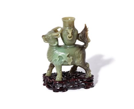 A JADE CARVING OF A MYTHICAL BEAST
The horned beast modelled striding and supporting a twin handled vase on it's back, carved