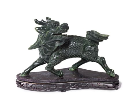 A SPINACH JADE CARVING OF A QILIN
Modelled striding, with its' head turned backwards, wood stand
16cm high including stand
Co