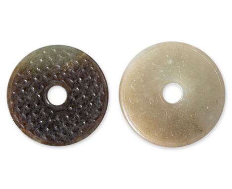 TWO CARVED JADE BI DISCS The first, of archaistic type, the stone of celadon and russet tones, carved to each side with a pat