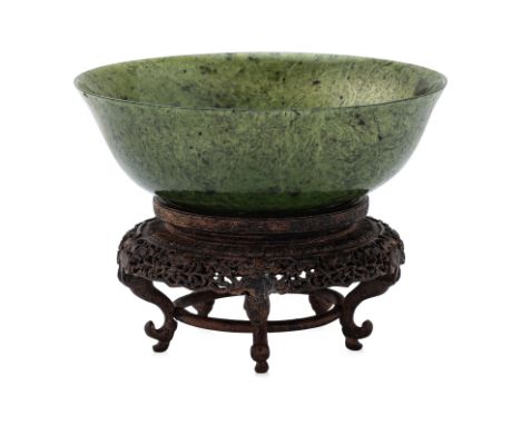 A SPINACH JADE BOWL ON STAND
19th/20th Century, thinly carved with slightly flared rounded sides raised on a short foot, on c