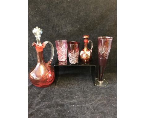 A group of ruby and cranberry coloured glass ware comprising a cranberry claret jug; two cut beakers, Bohemian trumpet vase; 