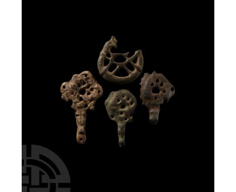 11th century A.D. Comprising: one C-shaped mount with tendril detailing; two irregular pierced pendants with beast-head suspe
