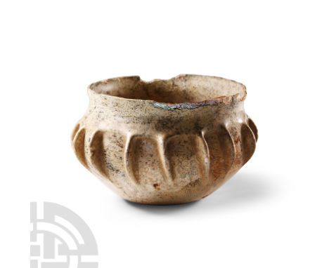 3rd-4th century A.D. With iridescent surface, flat bottom, vertical ribbed segmentation, slightly everted chipped rim. Cf. Wh