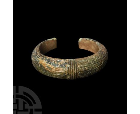 8th-12th century A.D. Featuring shallow engraved motifs and raised pellets and faux ropework, the penannular body tapering to