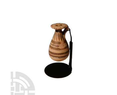 Circa 6th century B.C. The piriform bottle with broad everted rim and strap handle, polychrome painted dashes and concentric 