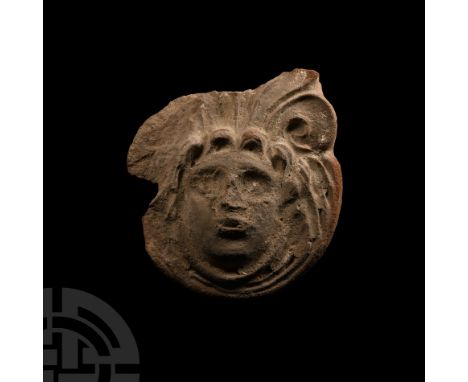 1st-2nd century A.D. Comprising a circular medallion from an architectural frieze, representing a mask crowned by vegetable c