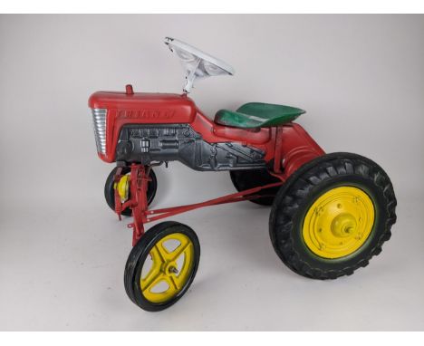 A mid 20th century Triangle red, green and yellow painted metal and plastic peddle tractor, with solid tyres, 57cm high, 72cm