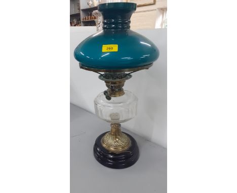 A Victorian oil lamp having a clear glass reservoir and a green shade on a brass stand and black glass mountLocation: 