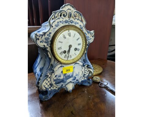 An early 20th century Delft style pottery cased 8-day mantel clock with white enamelled Roman dial, striking on a gong, with 