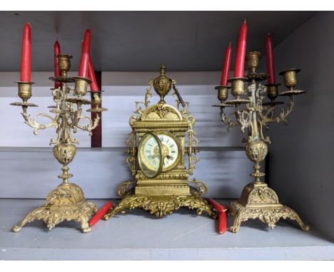 A Victorian brass cased clock garniture set, the ornate clock with gilt brass dial and cream enamelled Roman chapter ring, ho