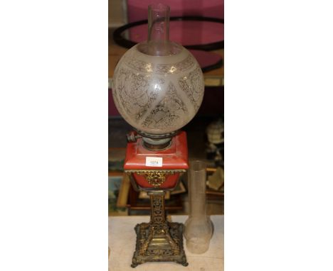 A Victorian gilt metal table oil lamp, the red pottery square reservoir with hinks burner together with etched spherical shad