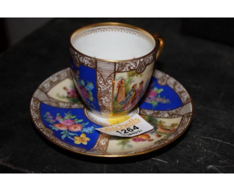 A Dresden porcelain cabinet cup and saucer decorated in colours with panels of flowers and figures within gilt rims