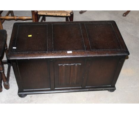 A dark elm rectangular blanket box or coffer of Ercol design with linen fold panel to front, 95 cm wide x 48 cm deep x 55 cm 