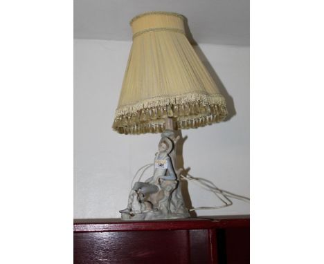A Lladro porcelain electric table lamp, modelled as a seated shepherd with dog, with shade for  same, 54 cm high  