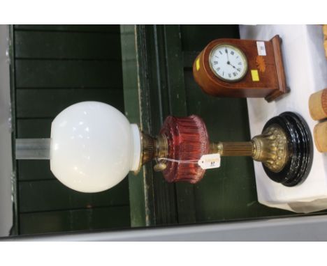 A 19th century oil lamp with red glass reservoir, white shade and chimney 
