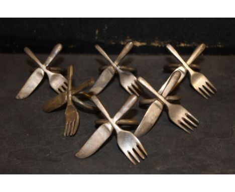 A set of six silver plated serviette rings, each modelled with a crossed knife and fork 