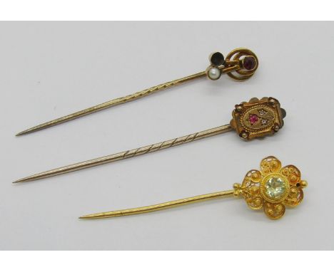 Three antique stick pins comprising a 15ct ruby and pearl example (one stone vacant), a Victorian 15ct ruby and diamond examp