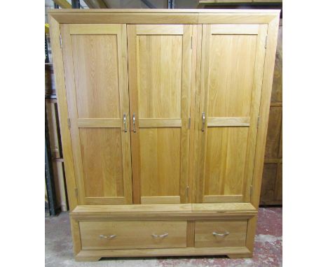 An Oak Furniture Land light oak triple wardrobe with bevelled and panelled framework over two drawers to base 185 cm high x 1