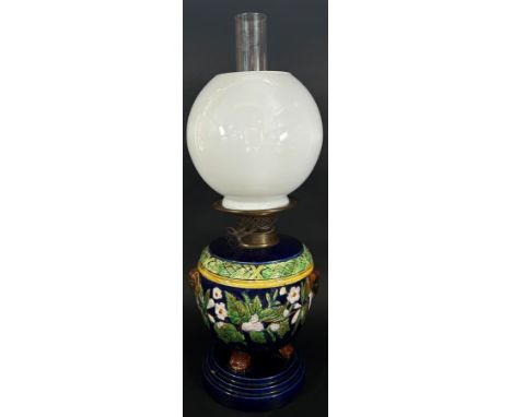 A Victorian Majolica type ceramic oil lamp with loose cover, Duplex burner and opaque globular shade and clear glass chimney,