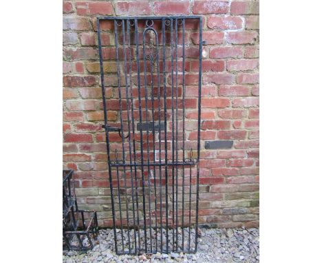 An old heavy gauge iron work pedestrian side gate with vertical rails, simple latch and open scrolled detail, 178 cm high x 7