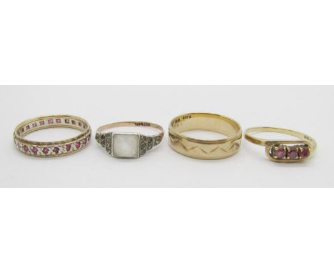 Four dress rings comprising a 9ct wedding ring, a 9ct three stone ruby ring, a 9ct ruby eternity ring and a 9ct and silver ex