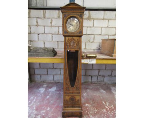 An early 20th century longcase clock with decorative chip carved case enclosing a circular silvered dial (complete with two w