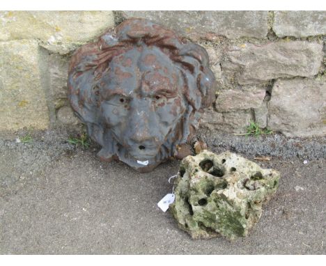 A cast iron water fountain head in the form of a lions mask and a piece of hag stone 30 cm x 15 cm approximately, together wi