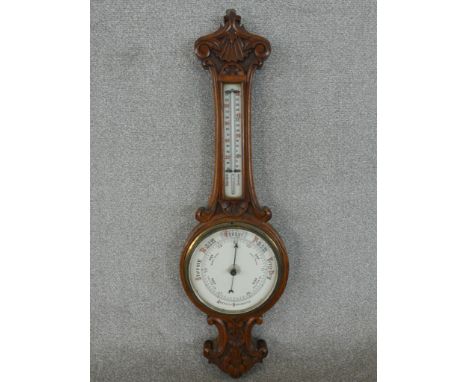 A late Victorian carved walnut aneroid banjo barometer, with an enamelled circular barometer dial, and a matching enamelled t