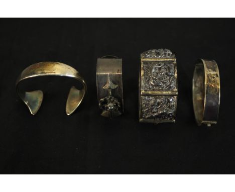 Four silver and white metal bangles (tested as silver), including a Hans Hansen abstract form torque bangle (signed), a white