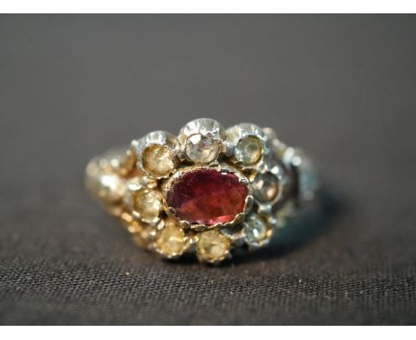 A 19th century red metal and silver closed back garnet and paste cluster ring, set to the centre with an oval foil backed gar